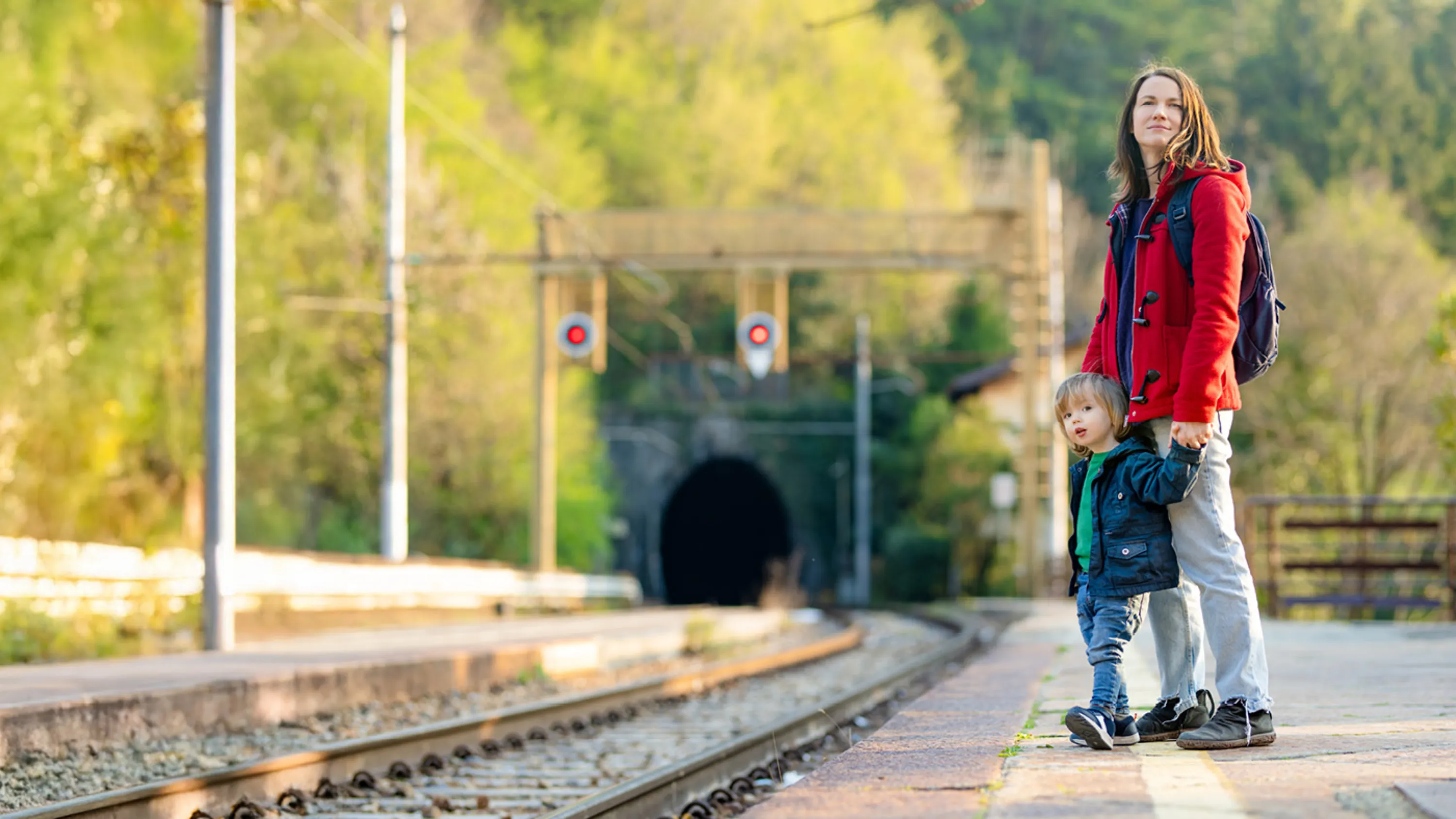 Eine Frau steht mit ihrem Sohn am Bahnsteig und wartet auf den Zug